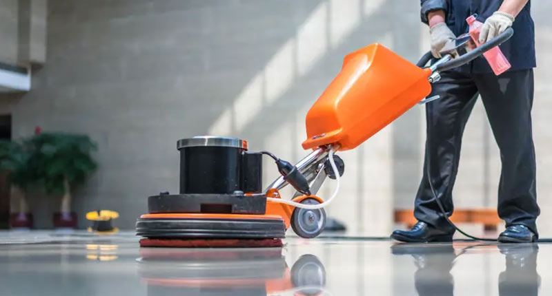 Janitor using floor cleaning machine