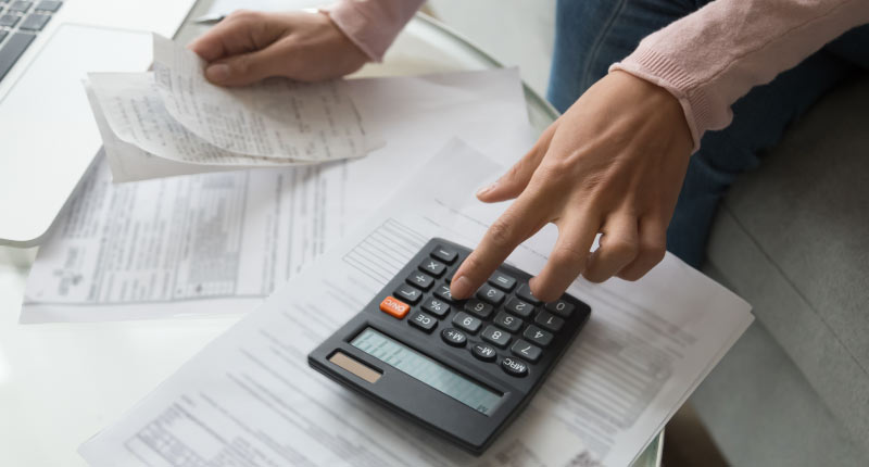 Close-up of a woman’s hands holding a receipt and calculating company payroll