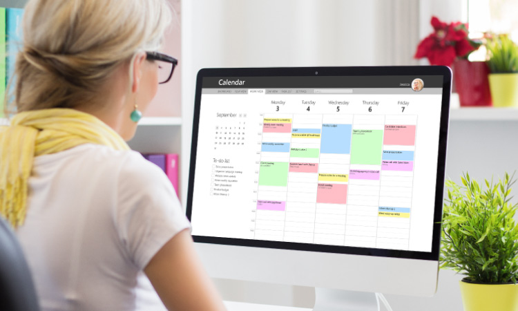 Woman using a calendar scheduling software on her desktop computer