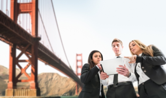 Two women and a man looking at work related documents on a tab with the golden gate bridge in the background