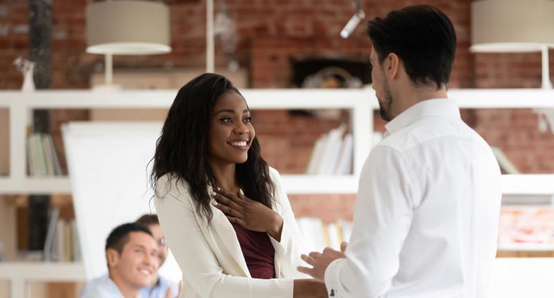 boss shakes hand with a female employee who is getting rewarded for a professional achievement