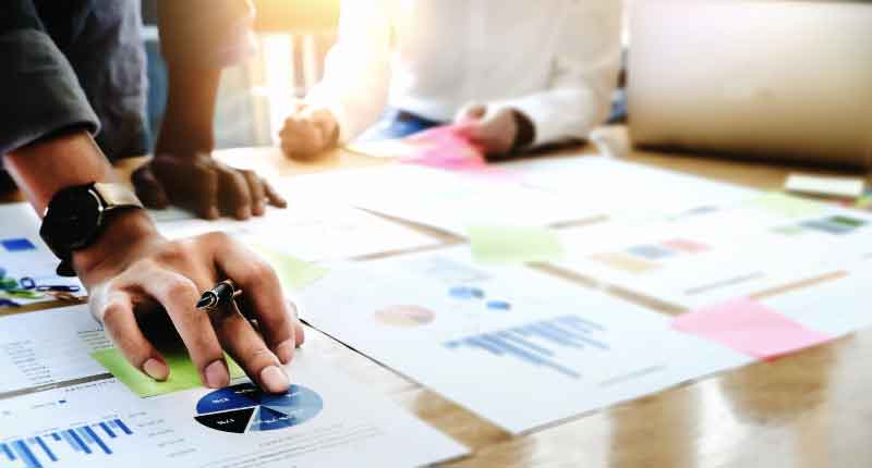 A person analyzing charts and other data on table